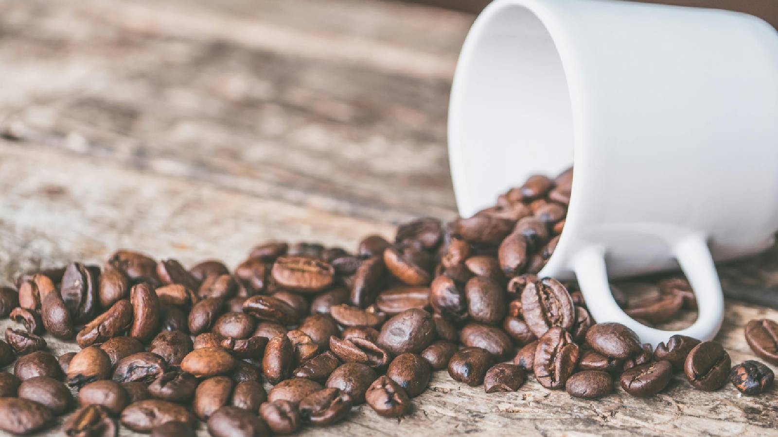 A cup of coffee with beans coming out.