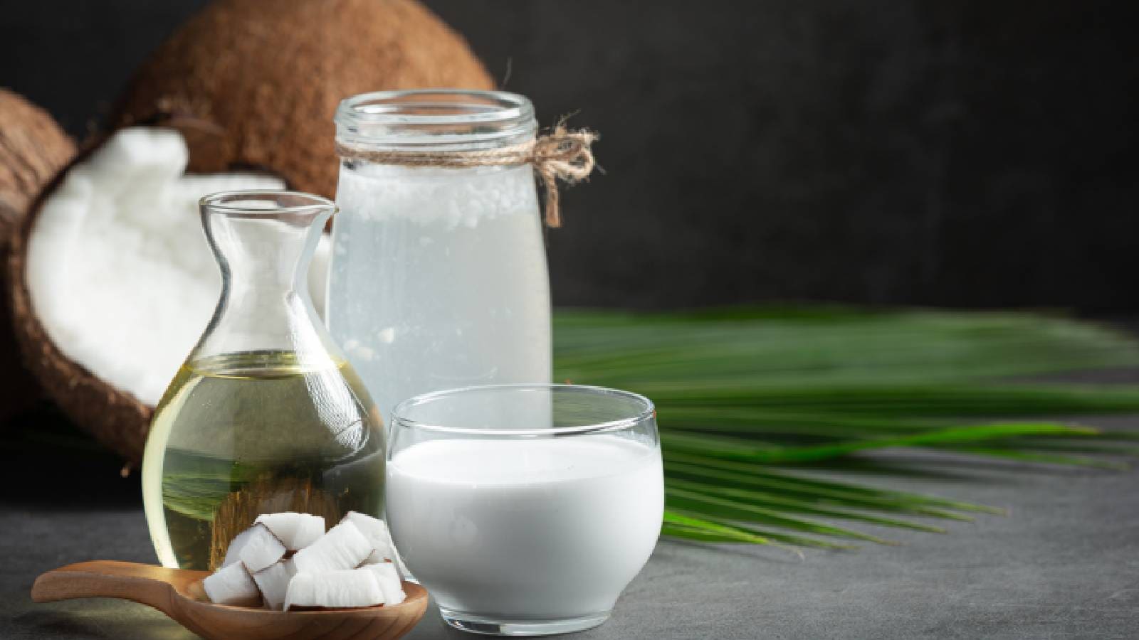 A glass of coconut milk, a bottle of coconut oil and a decanter or coconut water