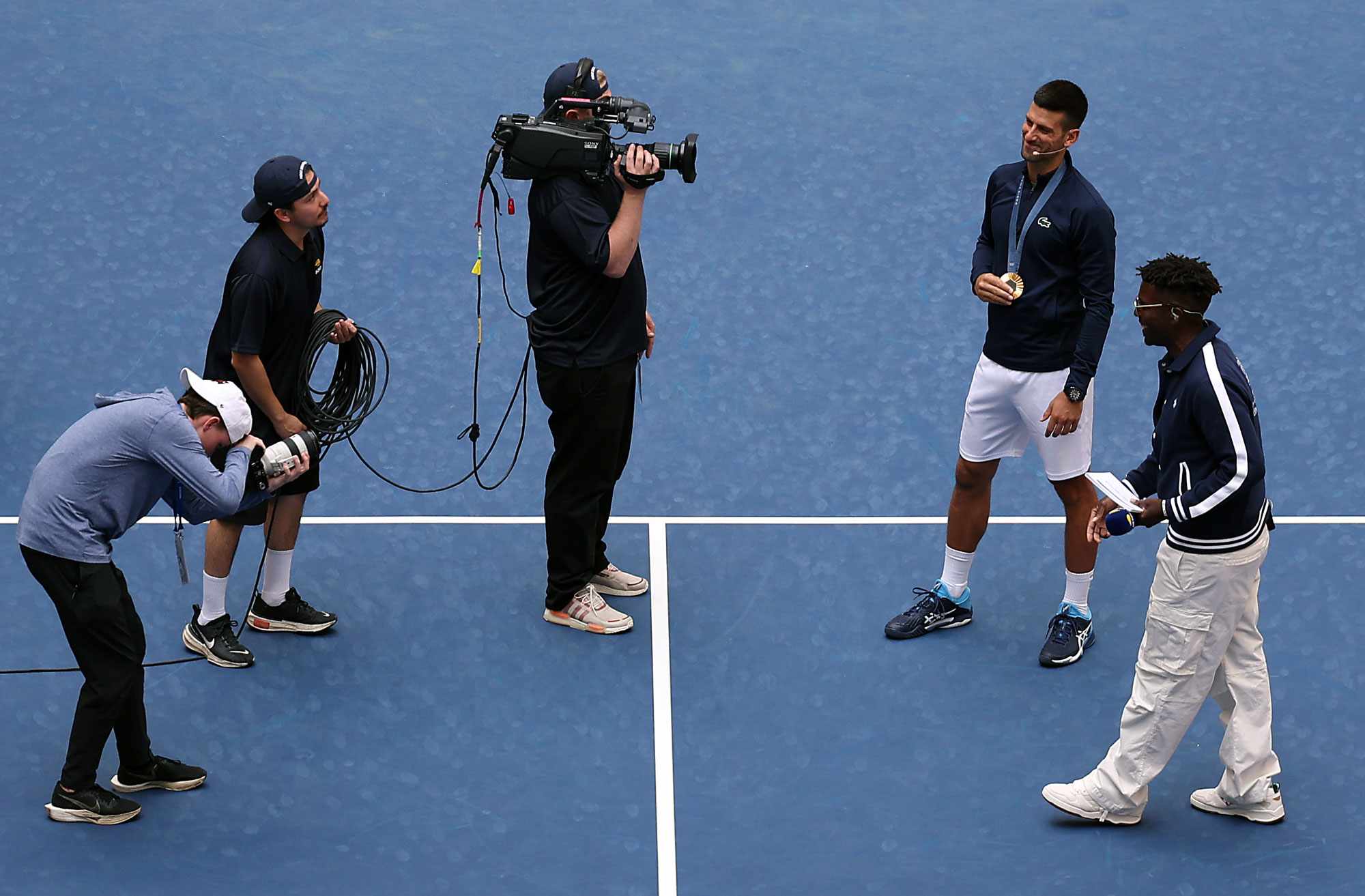 Novak Djokovic of Serbia shows off his gold medal while being introduced alongside Dude Perfect during Arthur Ashe Kid's Day ahead of the US Open at USTA Billie Jean King National Tennis Center on August 24, 2024