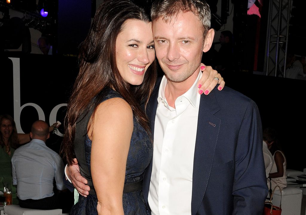 John Simm in a blue suit and white shirt hugging his wife Kate in a dress