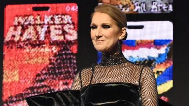 Celine Dion stands at a podium with a vibrant backdrop to present an award at City of Hope