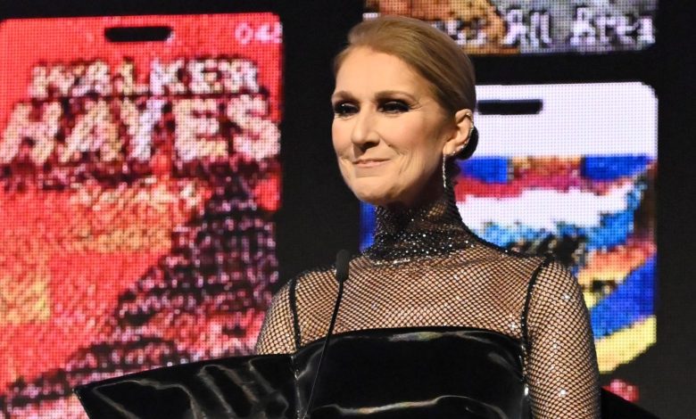 Celine Dion stands at a podium with a vibrant backdrop to present an award at City of Hope