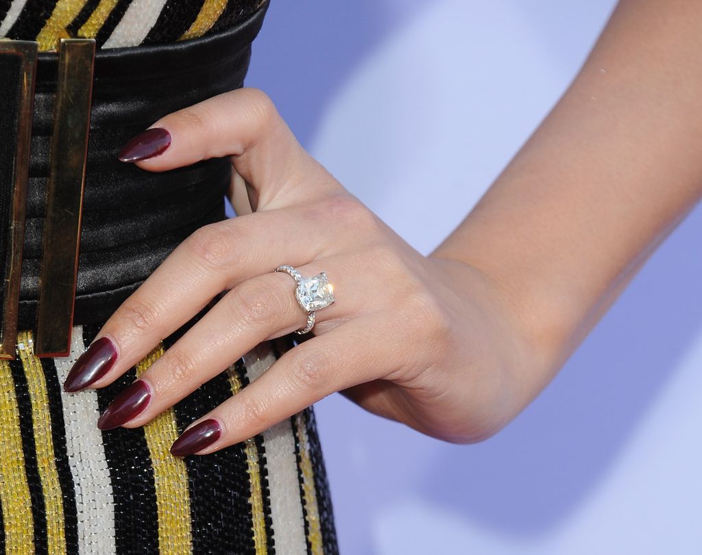 Chrissy Teigen hand with burgundy manicure and diamond ring