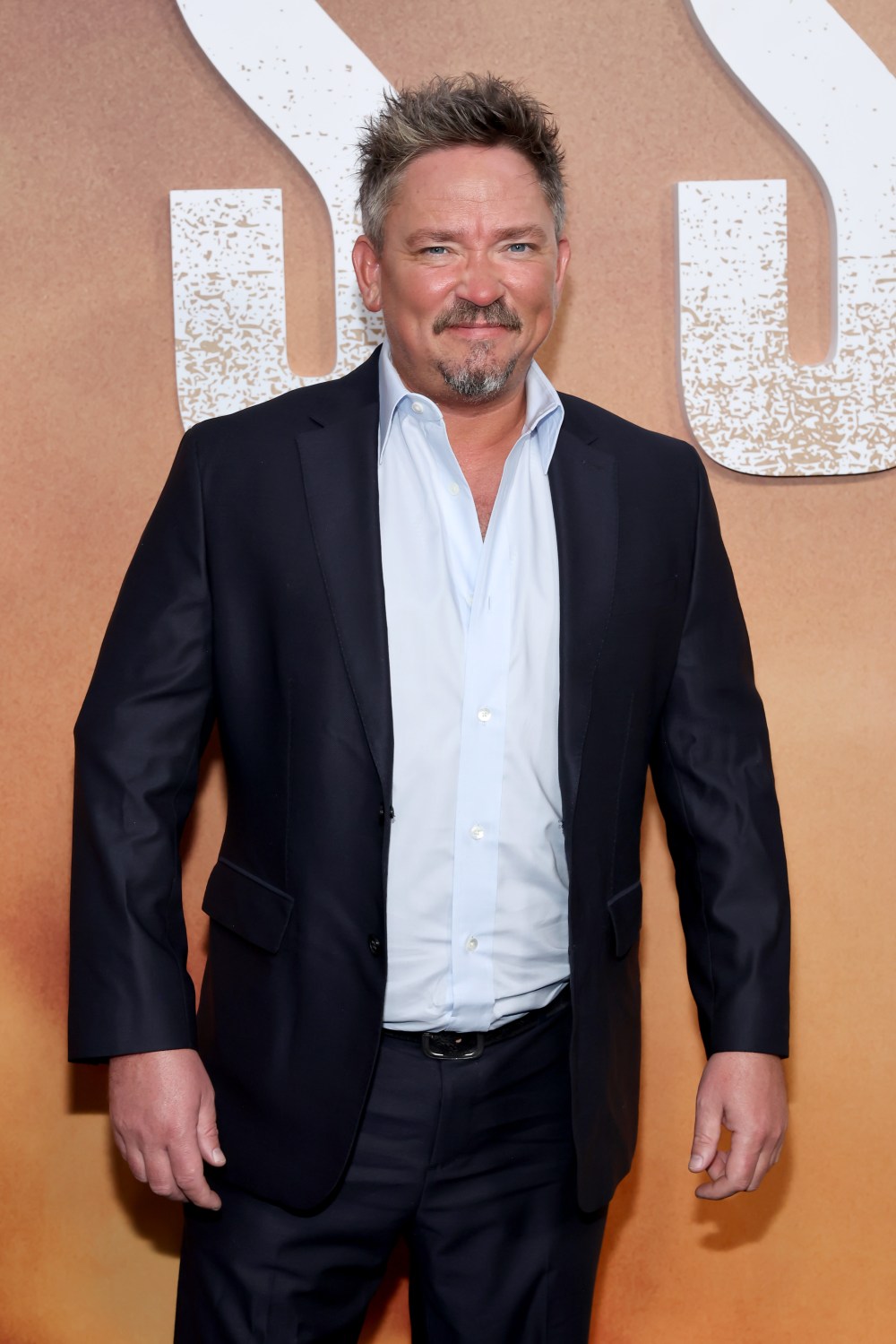 James Jordan poses in a navy suit and blue shirt.