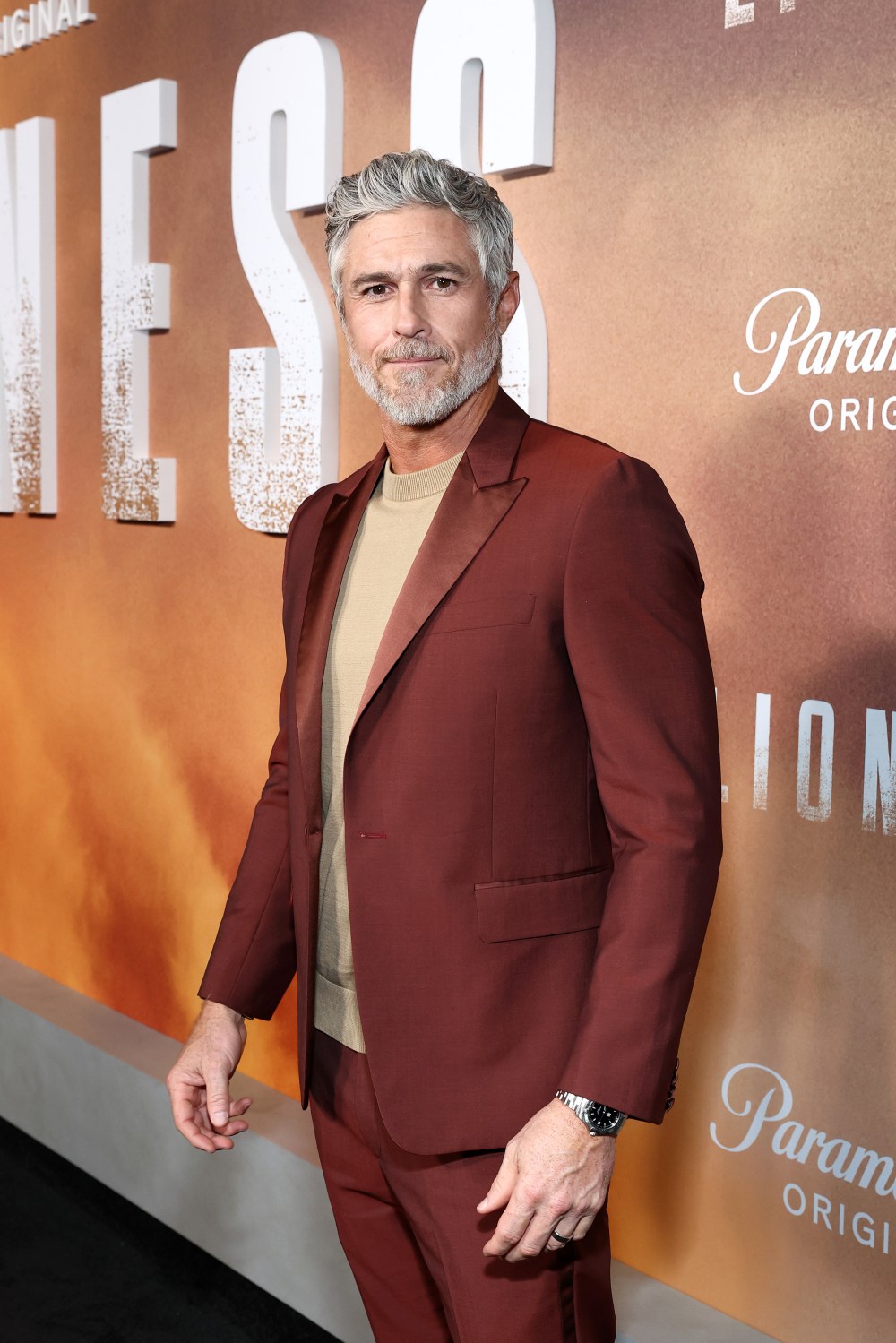 Dave Annable poses in a maroon suit at the Lioness premiere.