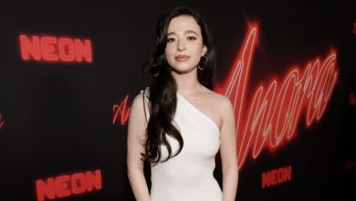 Mikey Madison poses in a white dress with gold bracelet at the premiere of Anora