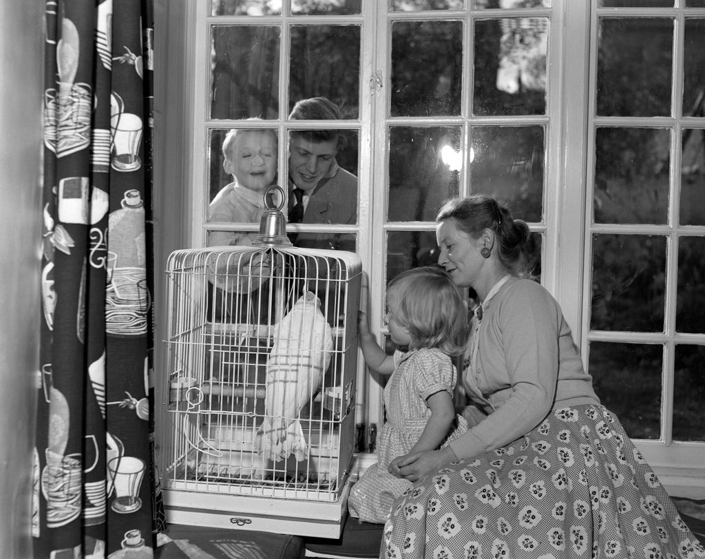 Black-and-white photo of a family-of-four with a bird in a cage