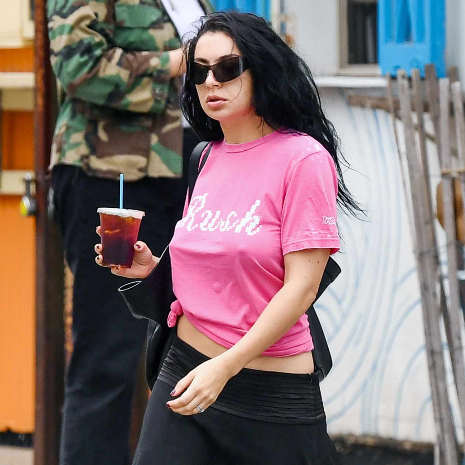 Charli XCX is spotted stepping out in New York City. The English singer wore a graphic pink t-shirt, black skirt, and knee high black boots.