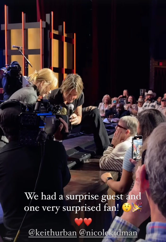 Still from a clip shared by the Grand Ole Opry Instagram of Nicole Kidman and Keith Urban taking a selfie with a fan from the stage, November 2024