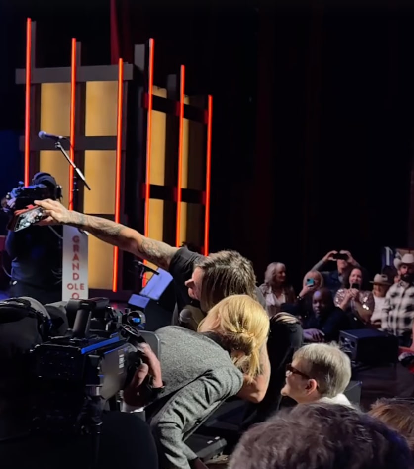 Still from a clip shared by the Grand Ole Opry Instagram of Nicole Kidman and Keith Urban taking a selfie with a fan from the stage, November 2024