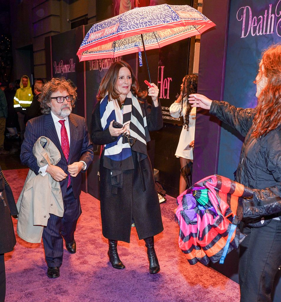 Tina and Jeff under umbrella walking onto red carpet 