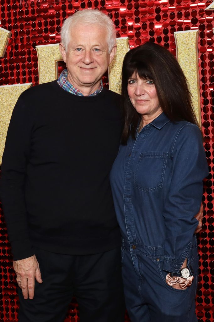 Richard Curtis in a black jumper standing with Emma Freud in a denim outfit