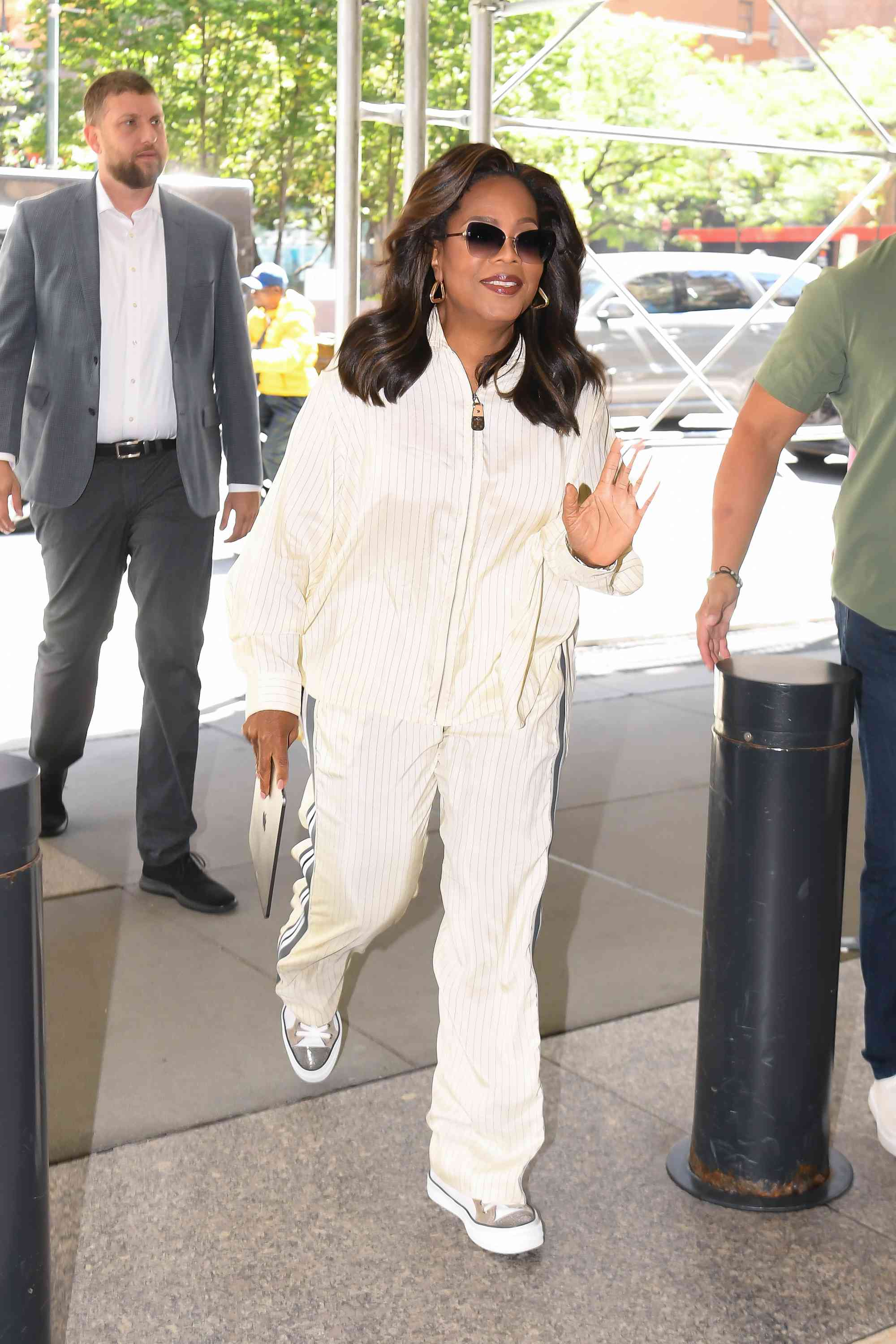 Oprah wearing cream knit track suit with brown sunglasses and gold earrings