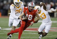 Ohio State Buckeyes quarterback Will Howard (18) runs with the ball ahead of Tennessee Volunteers defensive lineman Bryson Eason (20) and linebacker Edwin Spillman (13) during the CFP First Round game on December 21, 2024 at Ohio Stadium in Columbus, Ohio.