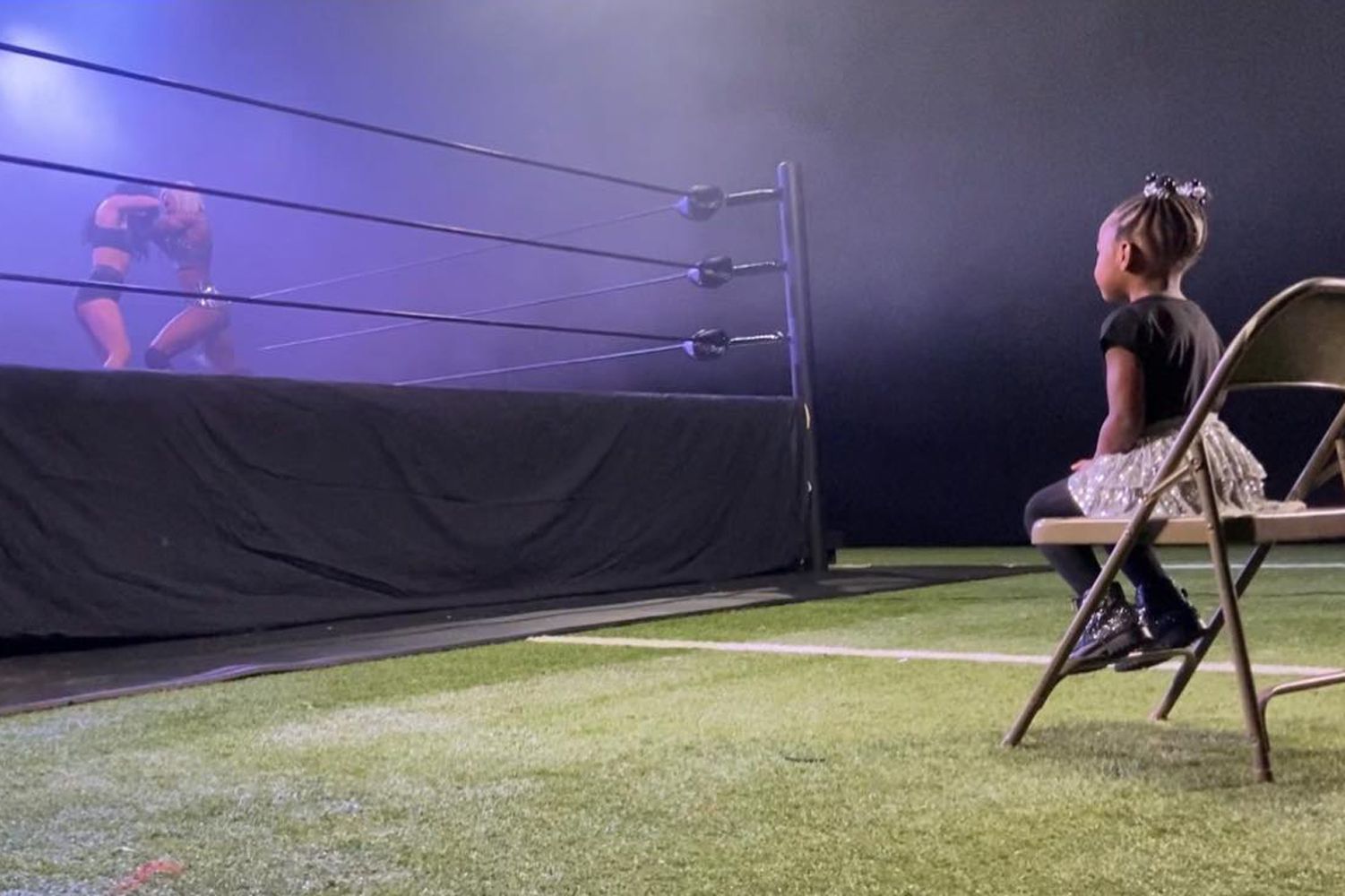 Jade Cargill wrestles in the ring while her daughter Bailey watches on the side.