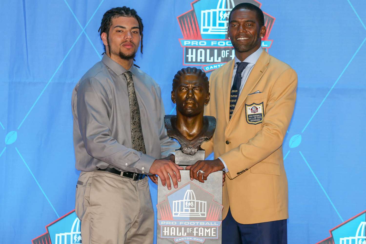 Randy Moss and son Thaddeus Moss pose next to Moss' bust during the 2018 Pro Football Hall of Fame Enshrinement Ceremony on August 4, 2018, at the Tom Benson Hall of Fame Stadium in Canton, OH.