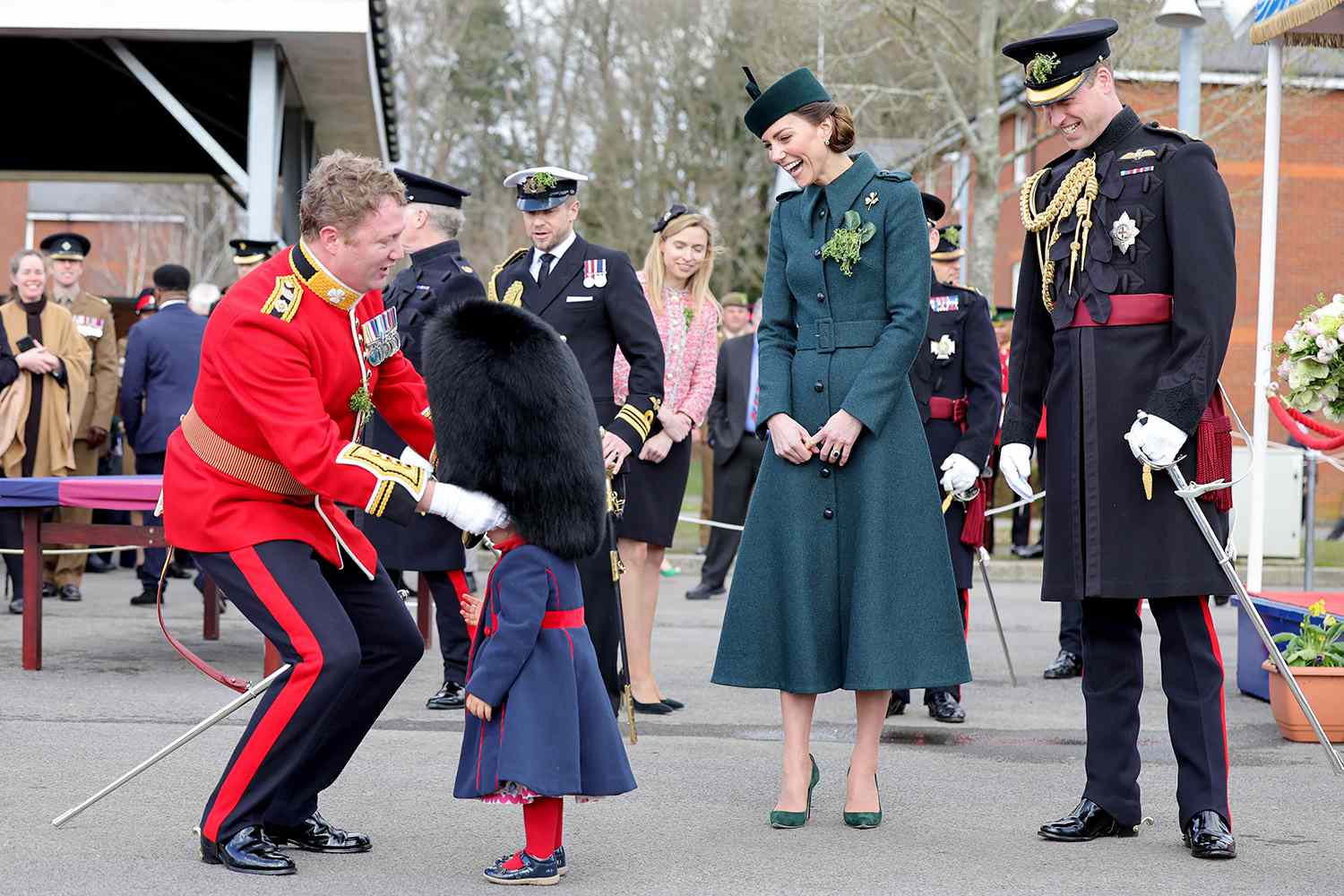 Catherine, Duchess of Cambridge and Prince William, Duke of Cambridge smile and laugh as Lieutenant Colonel Rob Money puts a bearskin hat on his 20-month-old daughter Gaia Money's head as they attend the 1st Battalion Irish Guards' St. Patrick's Day Parade at Mons Barracks on March 17, 2022 in Aldershot, England