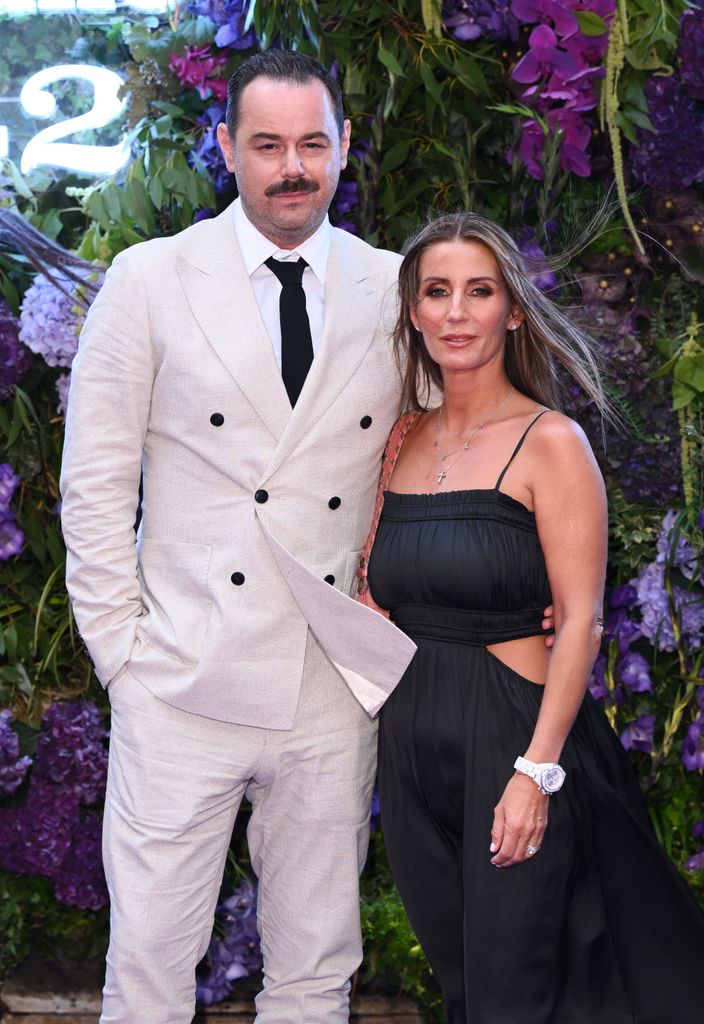 Danny Dyer in a white suit with his arm around Joanne Mas