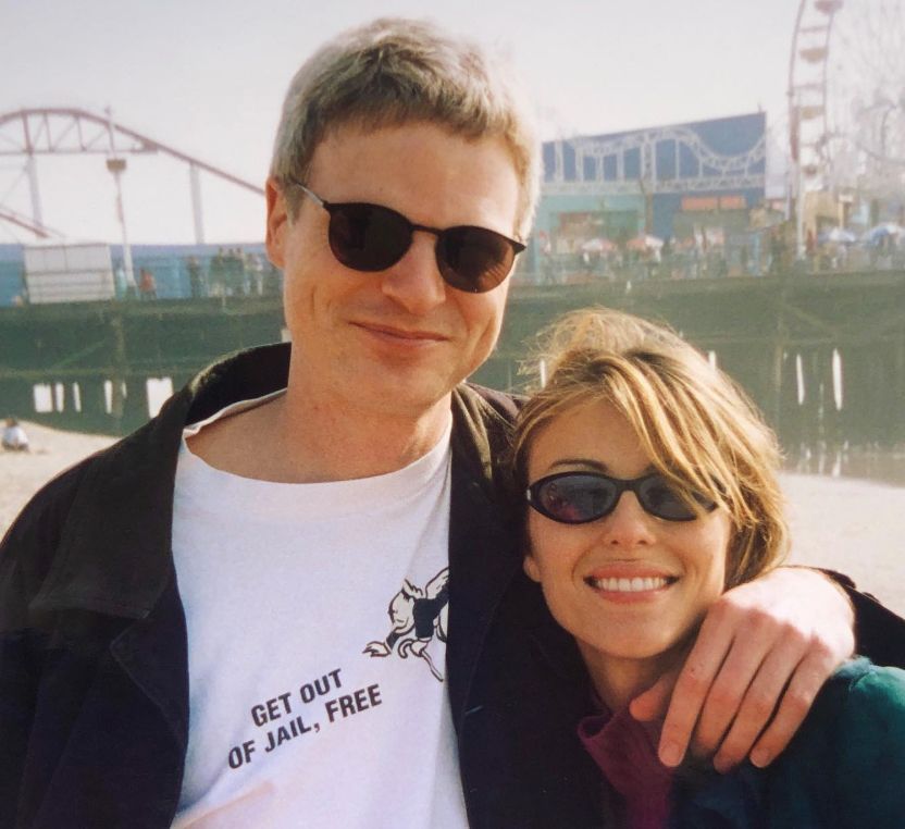 Steve Bing with his arm around Elizabeth Hurley in front of a pier with a fairground