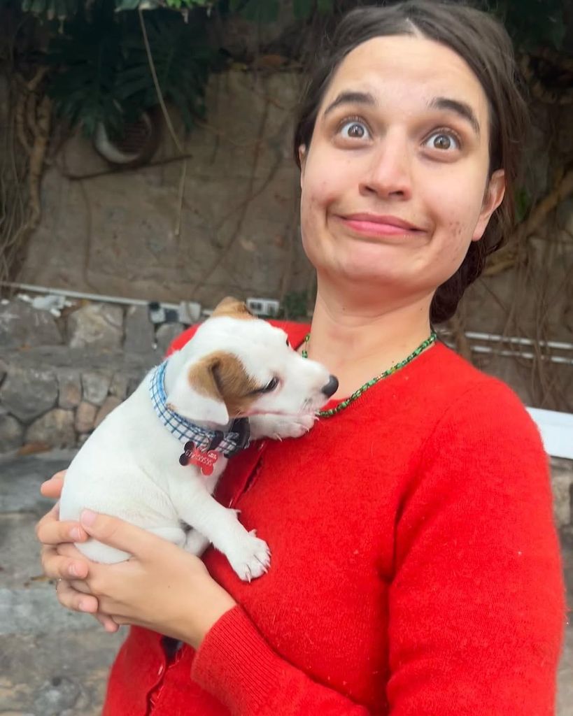 Tiger Lily Hutchence holding a dog wearing a red sweater