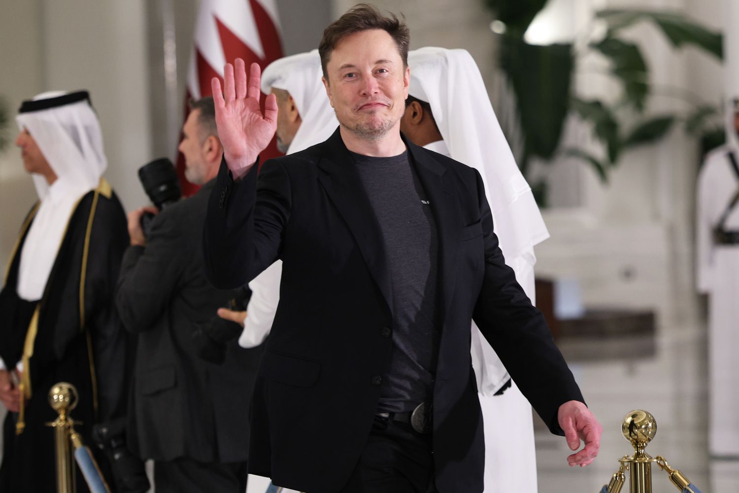 Elon Musk waves as he arrives for a state dinner at the Lusail Palac