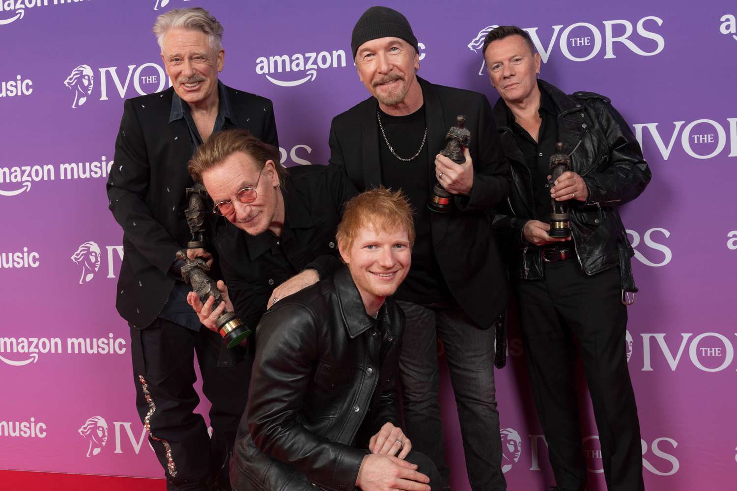 Adam Clayton, Bono, The Edge and Larry Mullen Jr. of U2 pose with the Fellowship of The Ivors Academy award presented by Ed Sheeran (front) in 