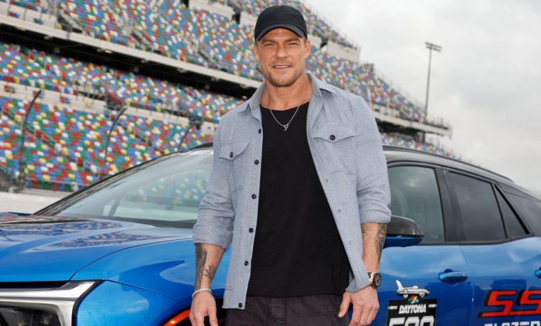 Alan Ritchson poses next to a Daytona 500 car.