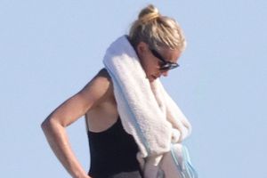 A person with sunglasses and towel wrapped around shoulders outdoors