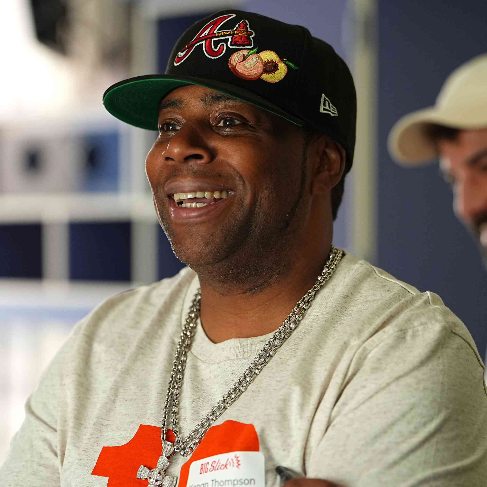 Kenan Thompson smiling, wearing a cap and T-shirt, in a casual setting