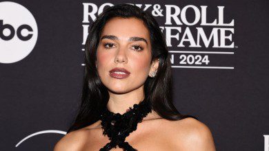 Dua Lipa poses against black backdrop at the Rock & Roll Hall of Fame in 2024.
