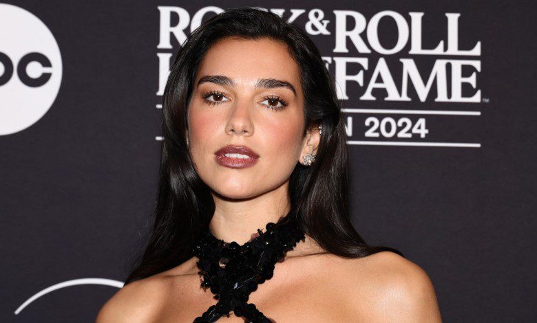 Dua Lipa poses against black backdrop at the Rock & Roll Hall of Fame in 2024.